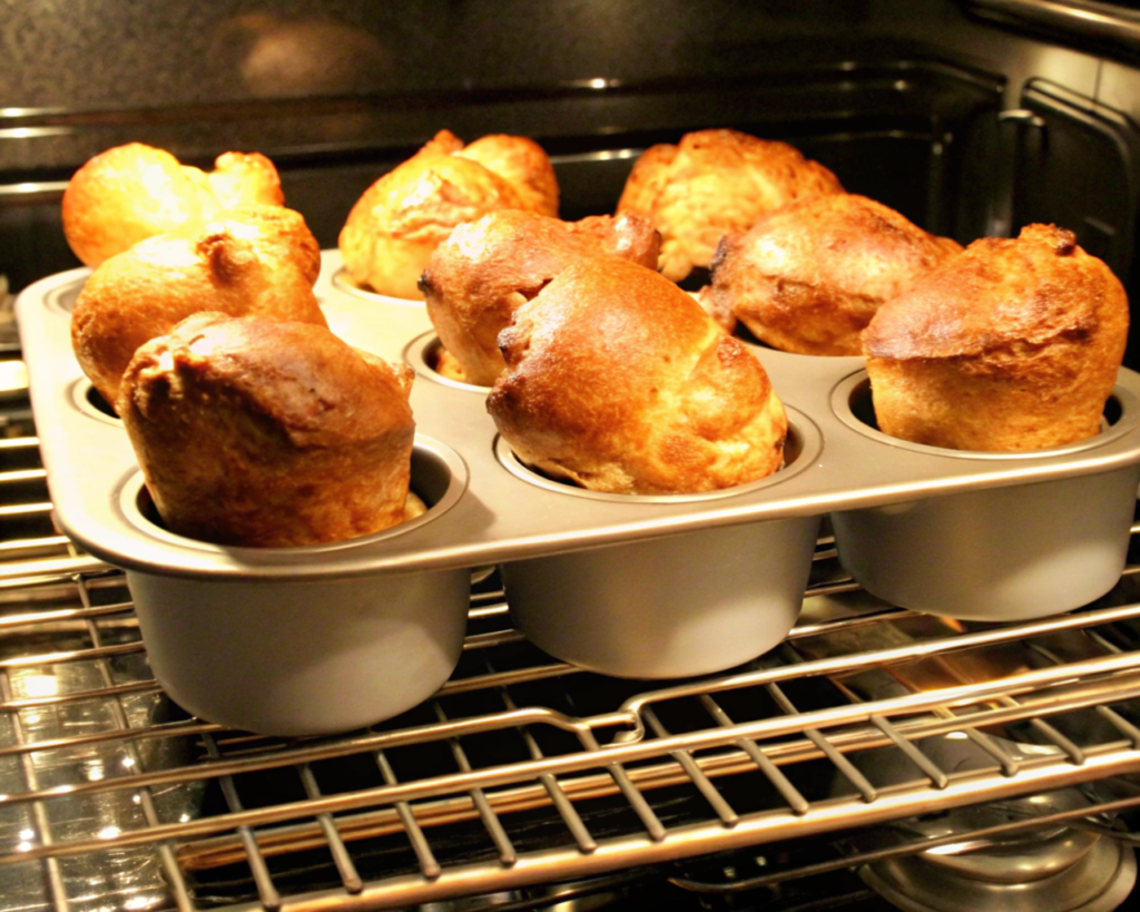  Golden-brown popovers baking in the oven, showcasing a creative twist on chicken pot pie with airy, crispy layers.