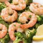 Air fryer shrimp and broccoli on a white plate with lemon wedges, showcasing juicy shrimp and roasted broccoli