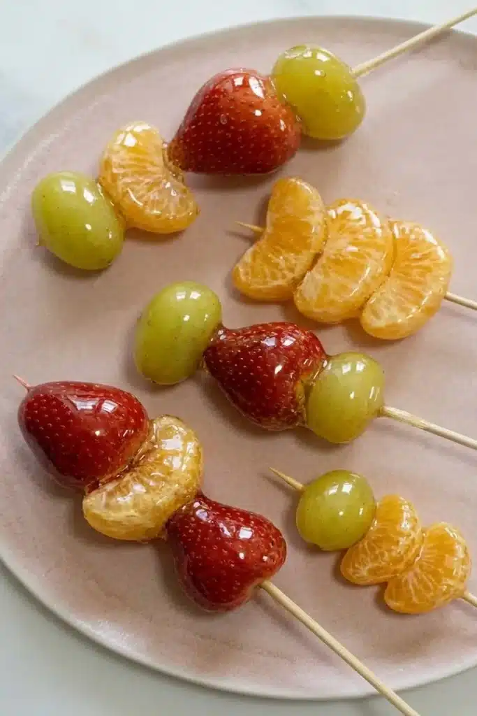 Tanghulu recipe: colorful candied fruit skewers with strawberries, grapes, and mandarines coated in crackly sugar shell.